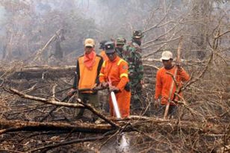 Petugas pemadam kebakaran, rangers, tentara dan aktivis lingkungan memadamkan kebakaran hutan di Kampar, Riau, 8 September 2015. Kabut asap dari kebakaran hutan di Indonesia, mengakibatkan pembatalan penerbangan dan peringatan bagi warga untuk tetap tinggal di dalam rumah.