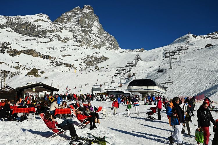 Wisatawan bermain ski dan beristirahat di bawah sinar matahari di bawah gunung Matterhorn (Monte Cervino) di resor ski alpen Breuil-Cervinia, Italia barat laut, pada tanggal 31 Desember 2021.