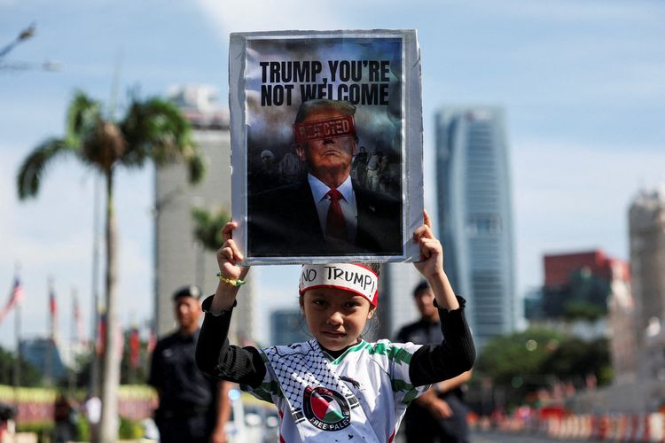 Seorang pengunjuk rasa pro-Palestina mengangkat plakat dalam aksi protes terhadap kehadiran Presiden AS Donald Trump di KTT ASEAN ke-47, di Kuala Lumpur, Malaysia, 26 Oktober 2025. 