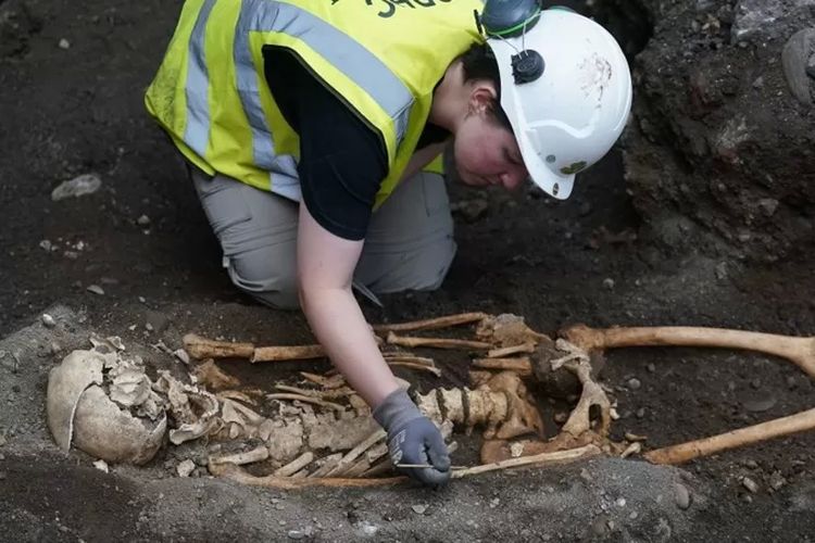 Seorang anggota tim arkeologi memeriksa sisa-sisa kerangka yang ditemukan selama pekerjaan persiapan untuk sebuah hotel baru di Kota Dublin.