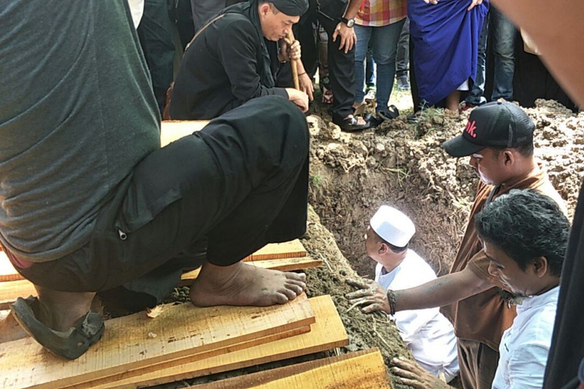 Penyanyi religi Opick (berpeci dan baju putih) turun ke liang lahat saat memakamkan istri keduanya, Wulan Mayasari, di TPU Semper, Cilincing, Jakarta Utara, Senin (19/3/2018).