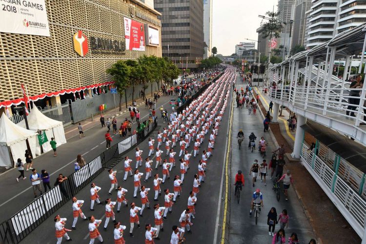 Para penari menampilkan tarian tradisional Poco-poco di sepanjang jalan  MH Thamrin, Jakarta, Minggu (5/8/2018). Sebanyak 65.000 orang penari turut serta dalam pemecahan rekor dunia tarian Poco-poco dan juga merupakan promosi menjelang Asian Games 2018.