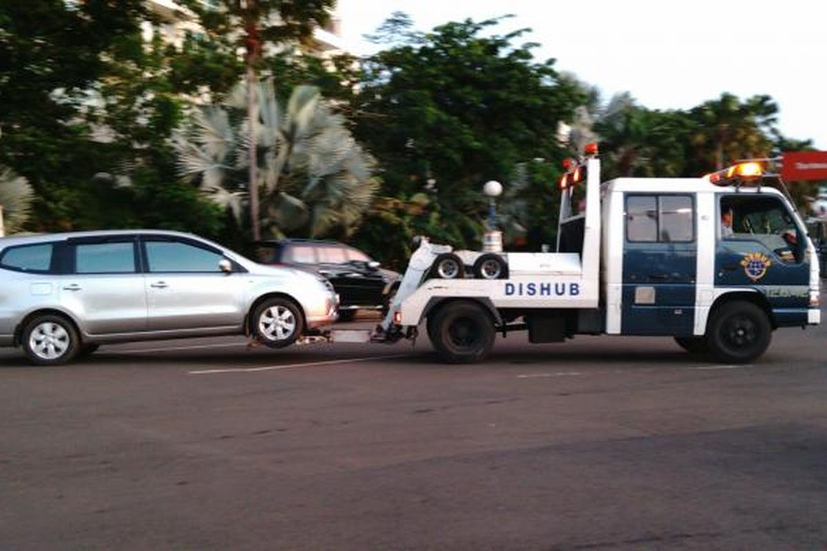 Sebuah mobil diderek oleh petugas Dishub DKI di dalam Ancol. Banyak kendaraan yang parkir sembarangan di bahu jalan pada perayaan tahun baru ini. Kamis (31/12/2015)