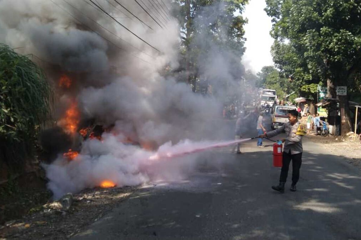Sejumlah petugas Polsek Sindangwangi Polres Majalengka Jawa Barat, berusaha memadamkan kobaran api yang membakar mobil minibus di jalan raya Sindangwangi, Minggu (8/1/2023).