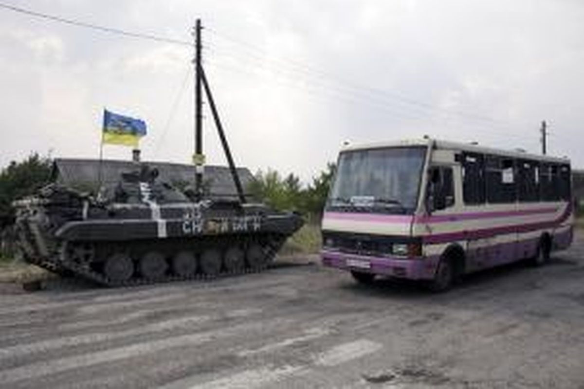 Sebuah bus melintas di dekat tank pasukan Ukraina yang berjaga di pinggiran kota Donetsk yang dianggap kota terbesar si Ukraina timur.
