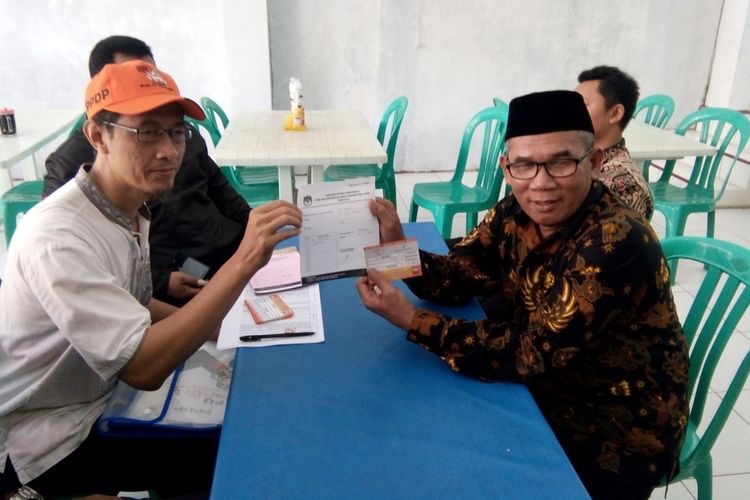 Bupati Demak,  M Natsir (pakai peci) menunjukan bukti coklit seusai didata oleh PPDP di rumahnya Kelurahan Bintoro RT 2  RW  3, Kecamatan Demak Kota,  Sabtu (20/1/2018)