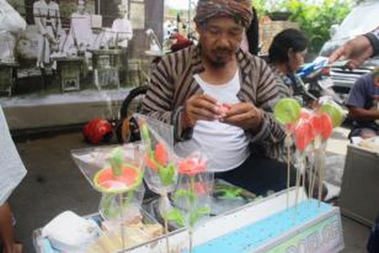 Munir, pedagang gulali di Malang, tengah sibuk membentuk permen gulali. 