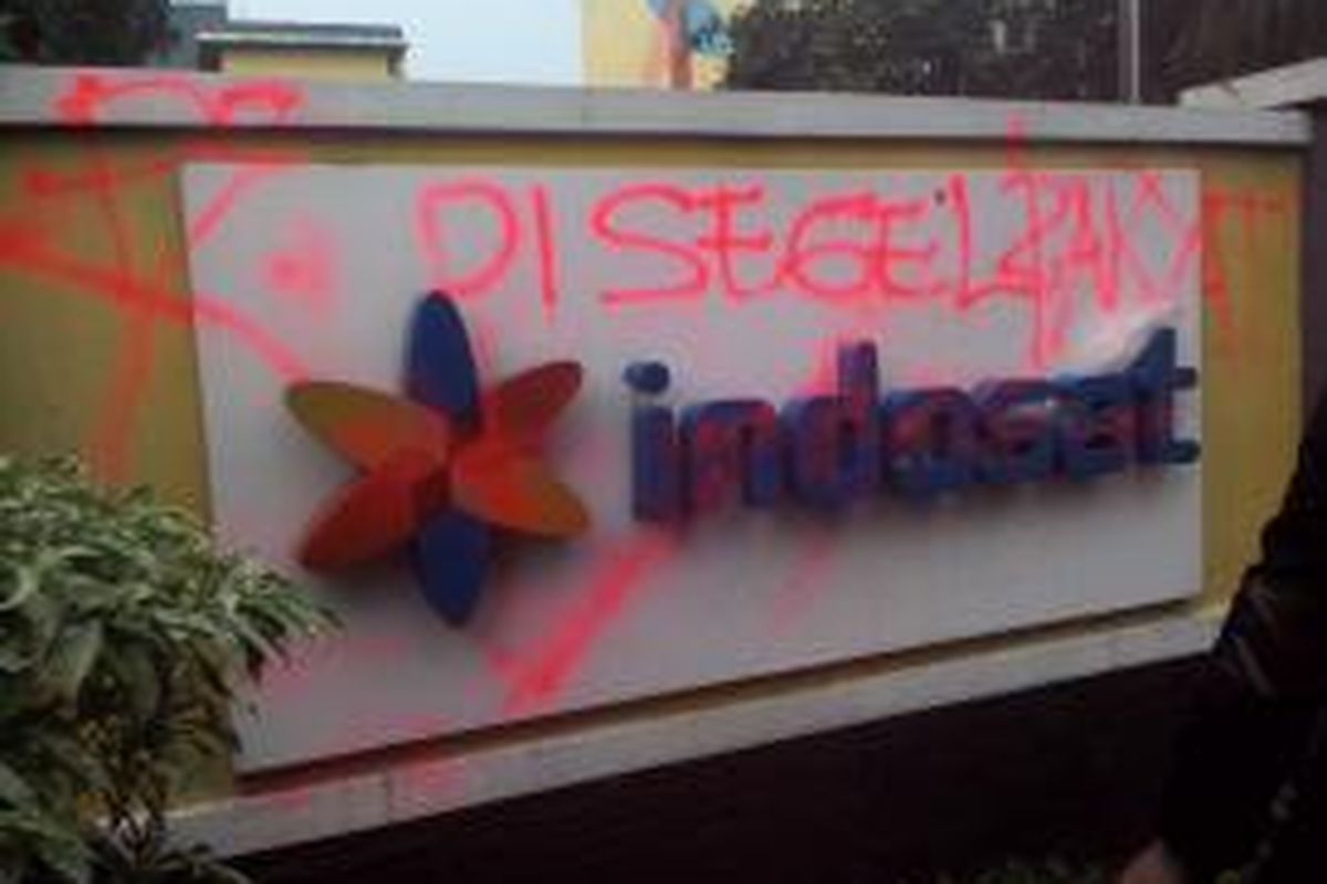 Para pengunjuk rasa di Bekasi mencoret-coret logo Indosat untuk memprotes iklan yang mereka anggap mengejek kota tersebut, Senin (12/1/2015).
