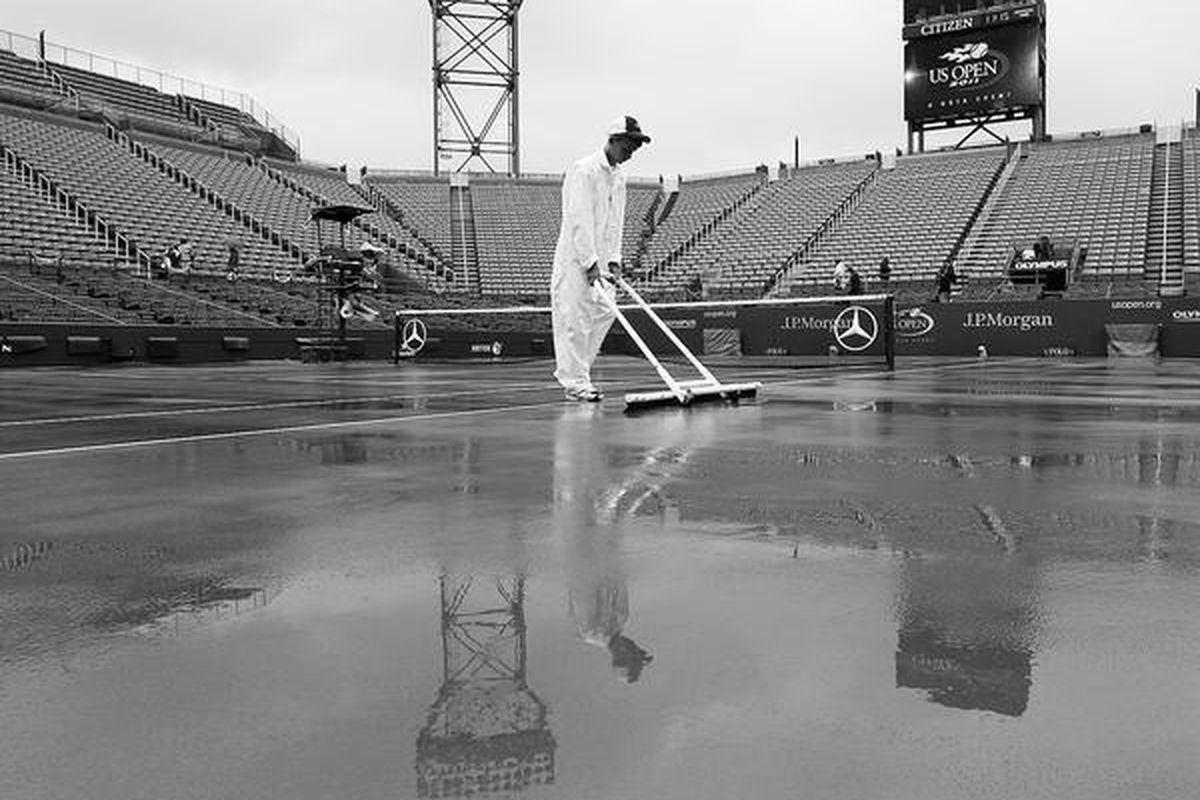 Pekerja mengeringkan lapangan Stadion Louis Armstrong, tempat perhelatan turnamen tenis AS Terbuka di New York, Selasa (6/9). Seluruh pertandingan pada hari itu ditunda karena hujan terus- menerus turun.