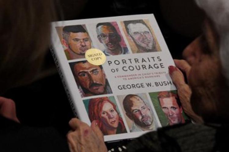 Warga yang hadir memegang buku karya mantan Presiden AS George W. Bush di the Ronald Reagan Presidential Library, Rabu waktu setempat. Buku itu bertajuk Portraits of Courage: A Commander in Chiefs Tribute to Americas Warriors. 
