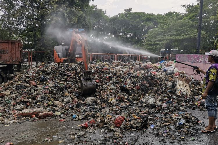Petugas saat menyemprot cairan penghilang bau di tumpukan sampah Terminal Purabaya