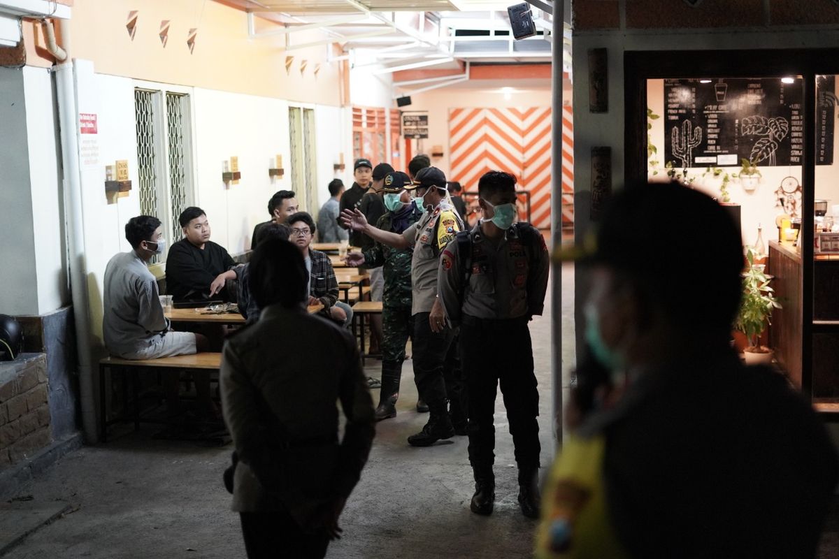 Polisi membubarkan kerumunan orang di sebuah kafe.