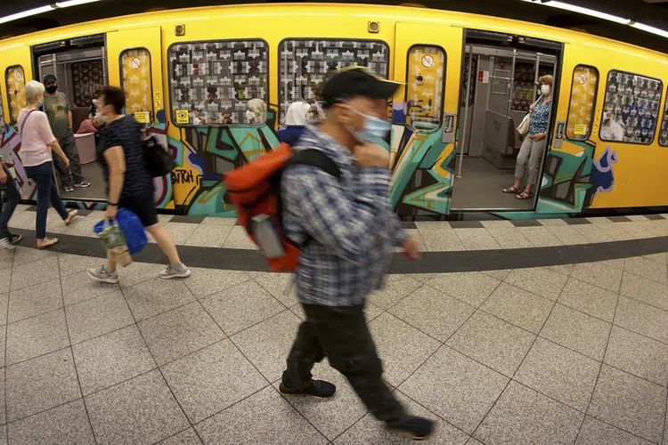 Seorang warga Jerman mengenakan masker untuk melindungi diri saat hendak naik kereta di Berlin, Jerman, Selasa (23/6/2020).
