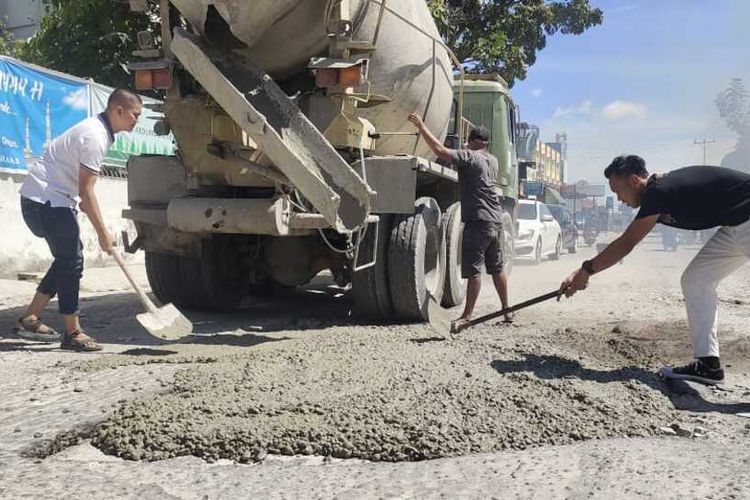 Bambang Nurdiansyah (baju putih kiri) bersama karyawannya mengecor jalan berlubang pakai uang pribadi di Jalan Delima, Kecamatan Bina Widya, Kota Pekanbaru, Riau, Selasa (14/4/2023).