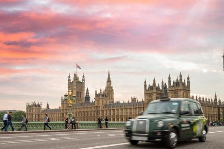 Taksi khas London melintas di depan gedung parlemen Inggris.
