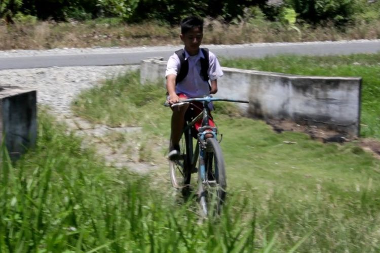 Meski penyandang difabel, Muhammad Amin Syam (11), siswa kelas VI Madrasah Ibtidaiyah (MI) Nurul Hikmah, di Desa Tolada, Kecamatan Malangke, Kabupaten Luwu Utara, Sulawesi Selatan, bisa mengendarai sepeda karena bantuan kaki palsu. Namun, kaki palsunya kini sudah tua. Dia lalu menulis surat kepada Presiden Joko Widodo dan berharap mendapatkan kaki palsu baru.