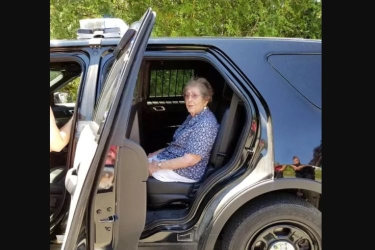 Simone (93) duduk di bangku belakang mobil patroli kepolisian Augusta Maine setelah dirinya ditahan oleh petugas.