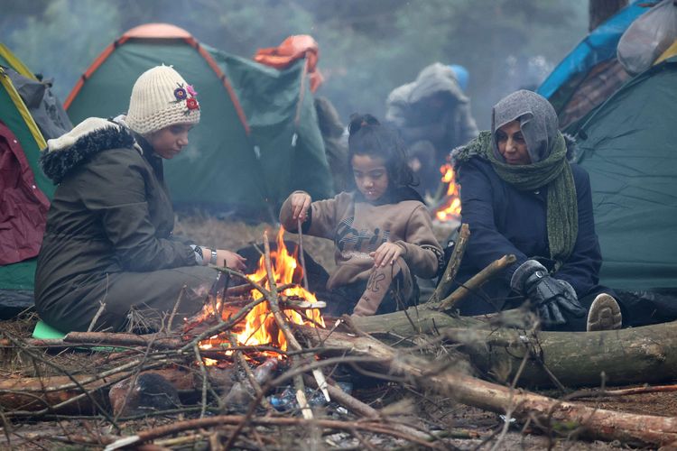 Sejumlah migran berkerumun di sekitar api unggun di hutan dalam suhu yang dingin di perbatasan Belarusia-Polandia, Rabu (10/11/2021). Polandia dan negara-negara Uni Eropa (UE) menuduh Belarusia mendorong para migran untuk secara ilegal melintasi perbatasan sebagai pembalasan atas sanksi yang dijatuhkan UE kepada Minsk atas pelanggaran HAM.