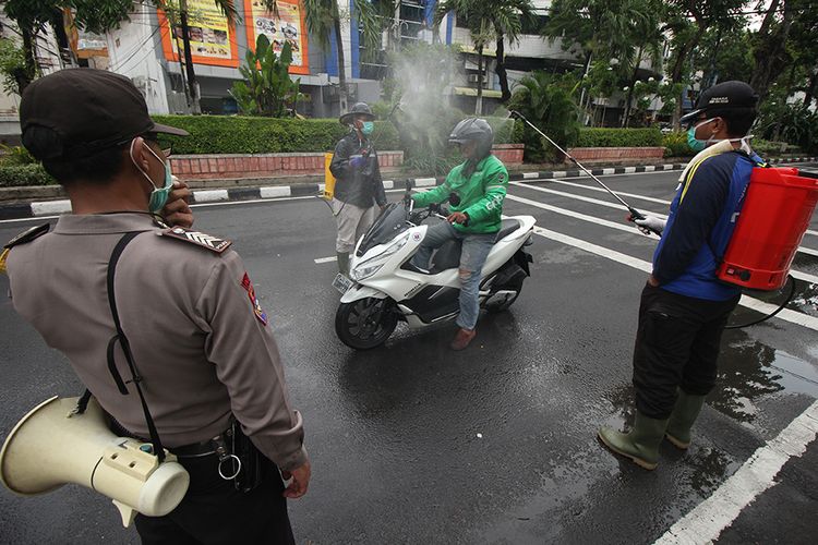 Polisi memberikan imbauan dan penyemprotan kepada pengemudi ojek daring di Jalan Bubutan, Surabaya, Jawa Timur, Jumat (3/4/2020). Kegiatan imbauan menghindari keramaian, penyemprotan disinfektan serta pemberian nasi bungkus yang dilakukan oleh pihak kepolisian bersama suporter sepak bola tersebut untuk mencegah penyebaran Virus Corona (COVID-19) dan meringankan beban ekonomi para pengemudi ojek daring.