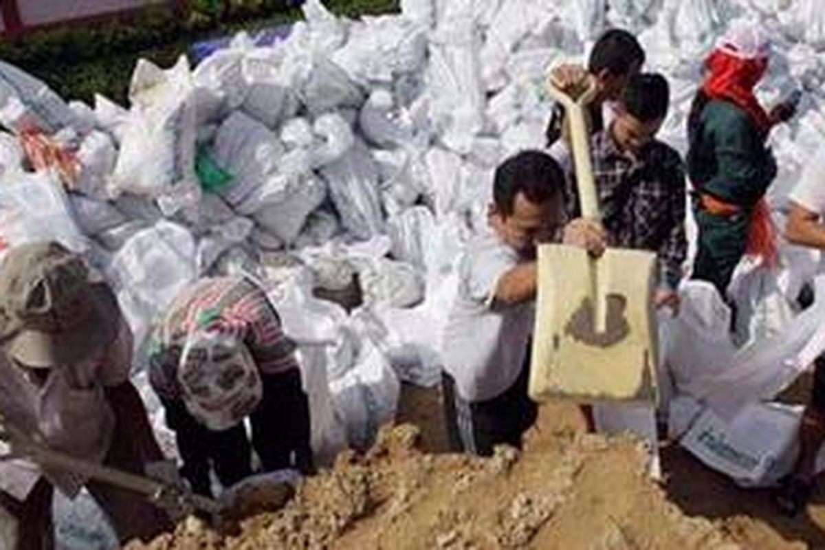 Para pekerja dan relawan mengisi karung dengan pasir yang akan digunakan untuk mencegah banjir masuk Bangkok.