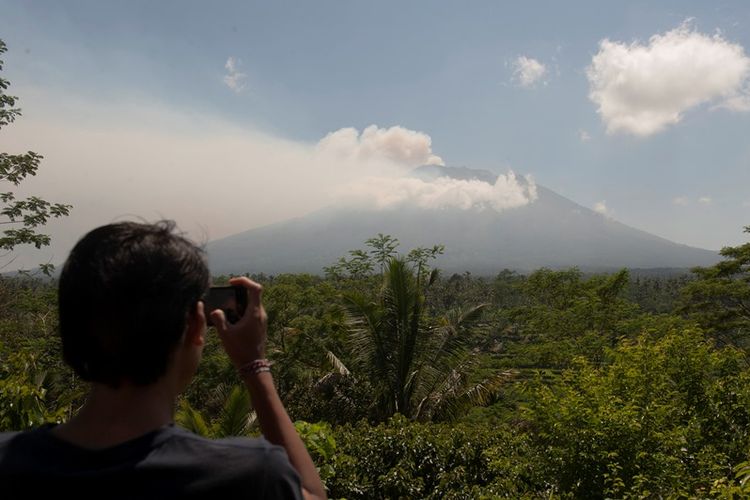 Warga memotret asap yang mulai mengepul dari kawah Gunung Agung dari Pos Pemantauan Desa Rendang, Karangasem, Bali, Selasa (19/9). Petugas pos pemantauan Gunung Agung telah mencatat tingkat kegempaan meningkat drastis dari 180 kali menjadi 366 kali dalam 24 jam terakhir.
