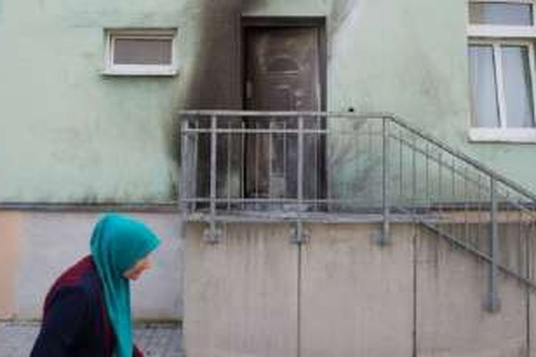 Seorang wanita Muslim berjalan melintasi pintu masuk Masjid Fatih Camii di Dresden, Jerman Timur, di mana sebuah bom rakitan meledak. 
