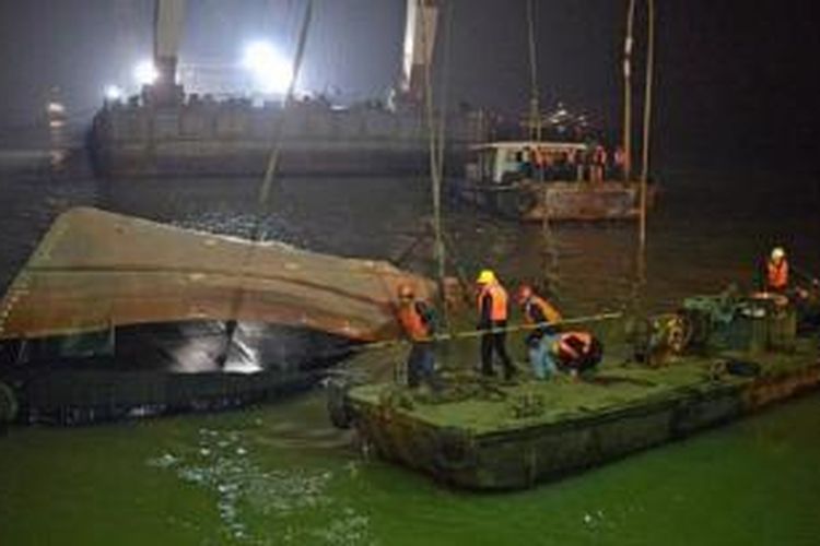 Regu pekerja penyelamat sedang mengangkat kapal tunda yang tenggelam di bagian utara Sungai Yangtze pada Kamis (15/1/2015) sore. Sebanyak 20 orang, termasuk waerga Singapura dan Jepang, dilaporkan hilang.

