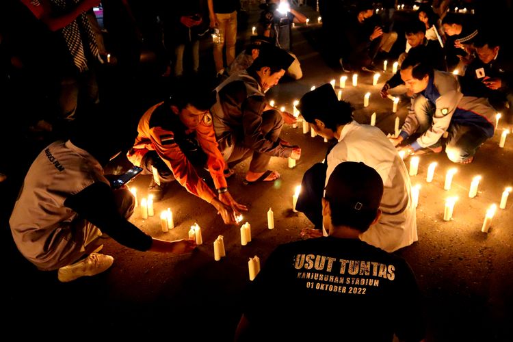 Seorang peserta menggunakan kaos bertulis usut tuntas sebelum doa bersama Aremania bahu membahu menyalakan lilin untuk memperingati 100 hari Tragedi Kanjuruhan di halaman Stadion Kanjuruhan Kepanjen, Kabupaten Malang, Senin (9/1/2023) malam.
