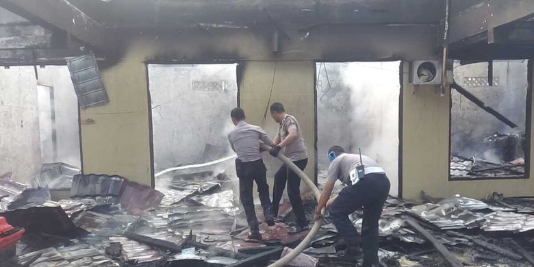 Petugas polisi melakukam pemadaman di salah satu ruang yang terbakar di Mapolres Ogan Ilir, Senin (17/1/2020)