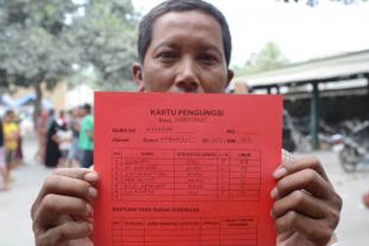 Munawar, warga Desa Kebonrejo menunjukkan Kartu Pengungsian saat didata di pengungsian bencana Gunung Kelud di TK Budi Mulia, Kecamatan Kepung, Kabupaten Kediri, Jawa Timur, Sabtu (15/2/2014). Pendataan terus dilakukan untuk menghindarkan warga pulang kembali ke rumah karena Gunung Kelud masih berstatus Awas. 