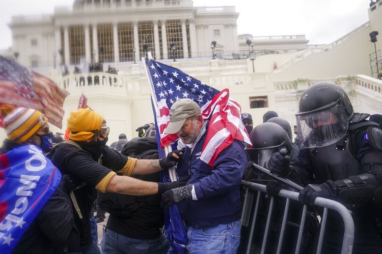 Pendukung Trump mencoba menerobos penghalang polisi, Rabu, 6 Januari 2021, di Capitol di Washington. 