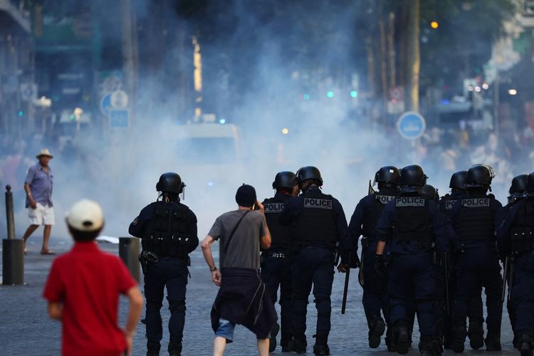 Petugas polisi berjalan saat mereka mencoba membubarkan pengunjuk rasa dengan gas air mata selama a
demonstrasi menentang polisi di Marseille, Perancis selatan pada 1 Juli 2023. Perancis sempat mengerahkan 45.000 petugas, didukung oleh kendaraan lapis baja ringan dan unit polisi untuk memadamkan kekerasan atas kematian Nahel yang berusia 17 tahun, yang terbunuh saat berhenti. di pinggiran Paris pada 27 Juni 2023.