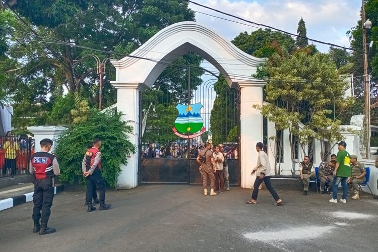 Gerbang Timur Pendopo Garut, Jawa Barat, Jumat (18/7/2025). Sejumlah aparat kepolisian dan Satpol PP berjaga usai insiden sejumlah warga tewas usai mengantre makanan di Pesta Rakyat yang merupakan rangkaian pernikahan Maula Akbar, putra dari Gubernur Jabar Dedi Mulyadi dan Wakil Bupati Garut Putri Karlina.