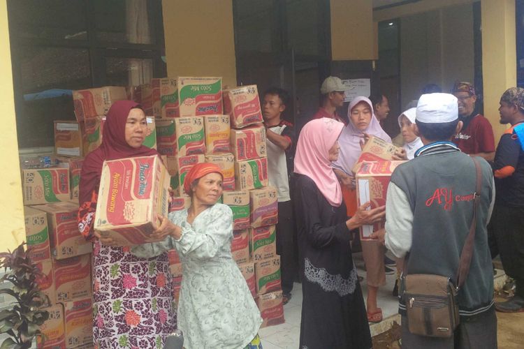 Sejumlah ibu-ibu ikut bergotongroyong menurunkan dus mi instan kiriman dari donatur di Posko Penanggulangan Bencana Alam di Dusun Cimapag, Desa Sirnaresmi, Kecamatan Cisolok, Sukabumi, Jawa Barat, Kamis (10/1/2019).