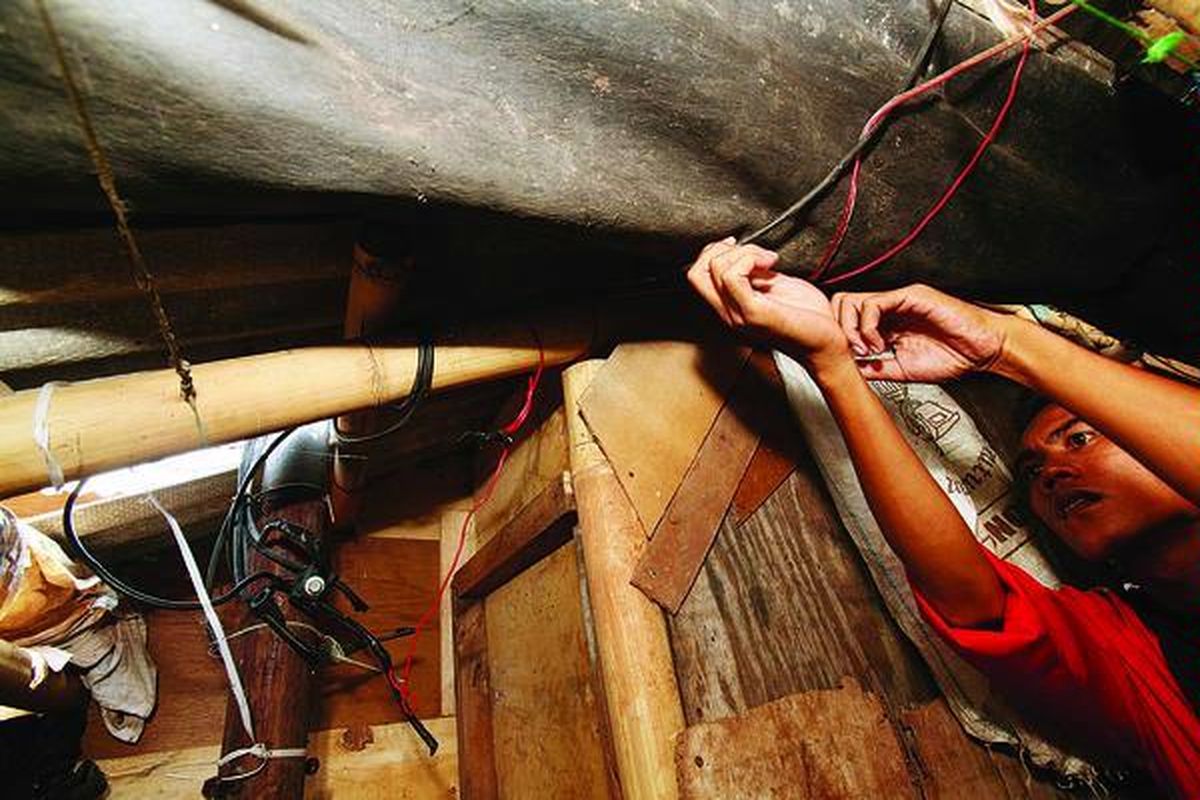Dari tiang di mana terdapat kabel master yang dulunya terlindung dalam kotak meteran listrik tegangan tinggi, aliran listrik disalurkan dengan jaringan yang dibuat sendiri oleh warga di kawasan permukiman padat penduduk di Penjaringan,  Jakarta, Senin (8/8). Listrik dialirkan ke sekitar 100 rumah yang secara kolektif membayar tagihan Rp 3 juta per bulan (atau Rp 30.000 per petak rumah).
