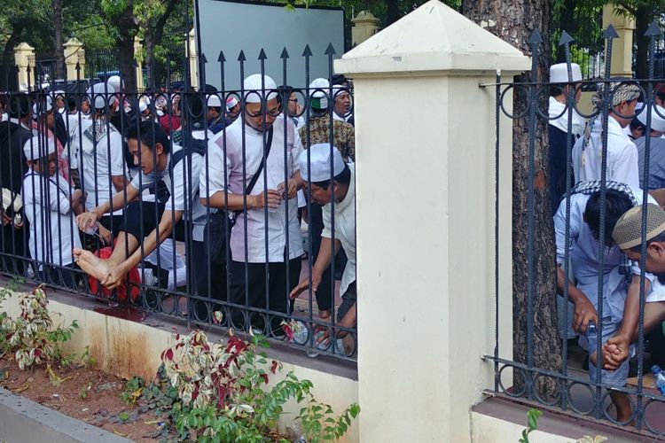 Massa pendukung Hizbut Tahrir Indonesia menunaikan salat zuhur berjemaah di depan gedung Pengadilan Tata Usaha Negara, Jakarta, Senin (7/5/2018) siang.