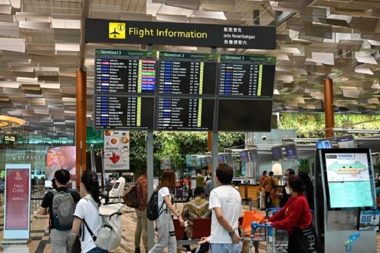 Penumpang pesawat yang memakai masker terlihat sedang mengantre  di Terminal 1 Keberangkatan Bandara Internasional Changi, Singapura.