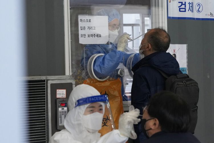 Petugas medis mengambil sampel hidung dari orang-orang di tempat pengujian virus corona darurat di Seoul, Korea Selatan, Selasa, 14 Desember 2021.