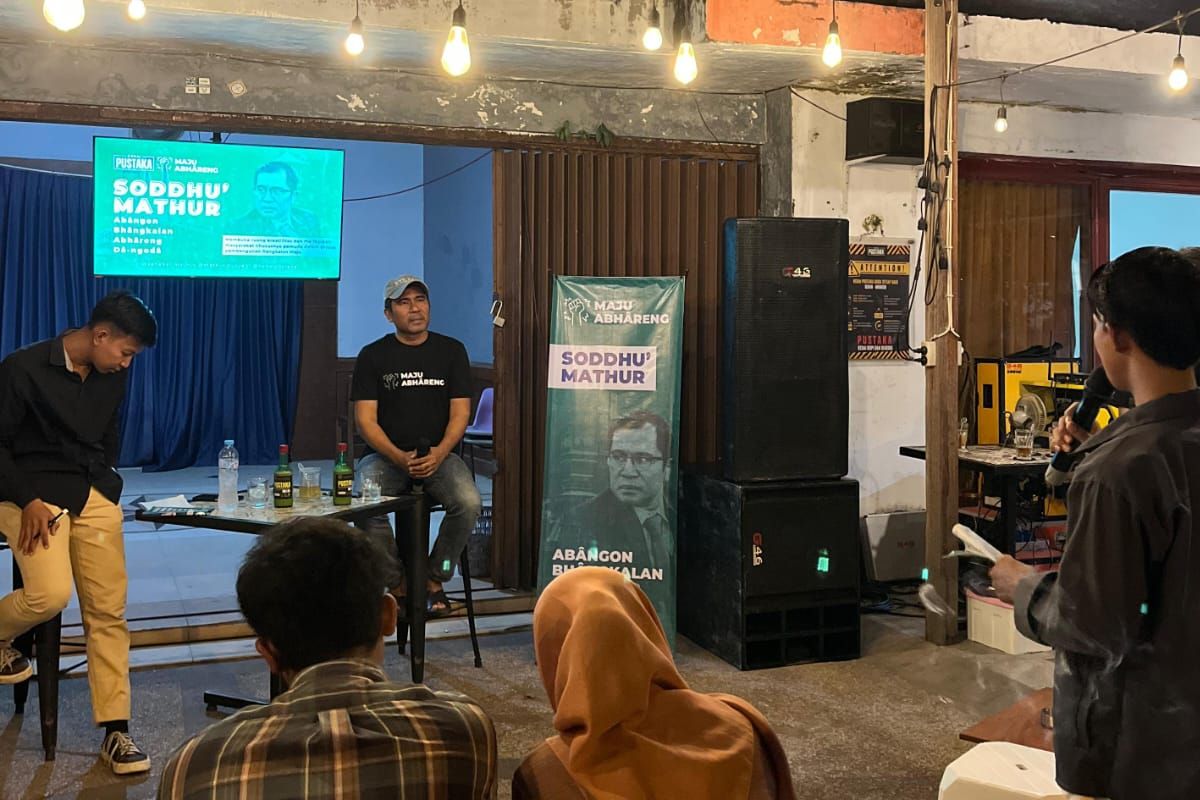 Calon bupati Bangkalan nomor urut 2, Mathur Husyairi (pakai topi) saat hadir dalam acara Soddhu' Mathur bersama beragam komunitas anak muda di Kedai Kopi Pustaka, Jalan Kartini Nomor 10, Kelurahan Kraton, Bangkalan, Jawa Timur, Jumat (4/10/2024) malam.
