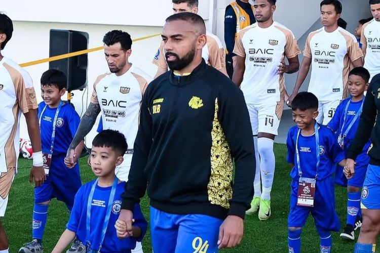 Pemain Arema FC Dalberto Belo menggandeng player escort dari Dendi Santoso Soccer School (DSSS) jelang kick off pekan ke-5 Super league 2025-2026 melawan Dewa united yang berakhir dengan skor 1-2 di Stadion Kanjuruhan Kepanjen, Kabupaten Malang, Sabtu 913/9/2025) sore.