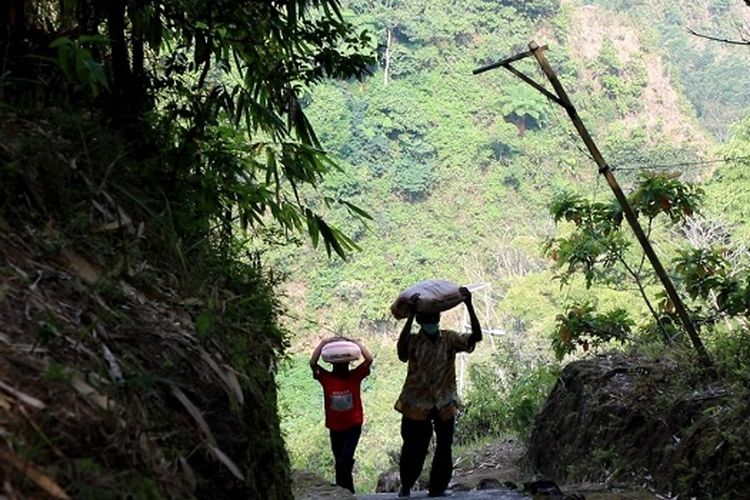 Sutarno, saat memanggul bantuan 50 kilogram sak semen menuju rumahnya. 