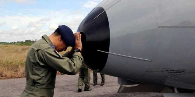 Seorang anggota TNI AL berdoa di hidung pesawat CN-235 saat akan memulai operasi pencarian pesawat AirAsia QZ8501, di Pangkal Pinang, Pulau Bangka, 30 Desember 2014. Pesawat AirAsia QZ8501 mengangkut 155 penumpang serta 7 kru, jatuh pada Minggu pagi, saat penerbangan dari Surabaya ke Singapura.
