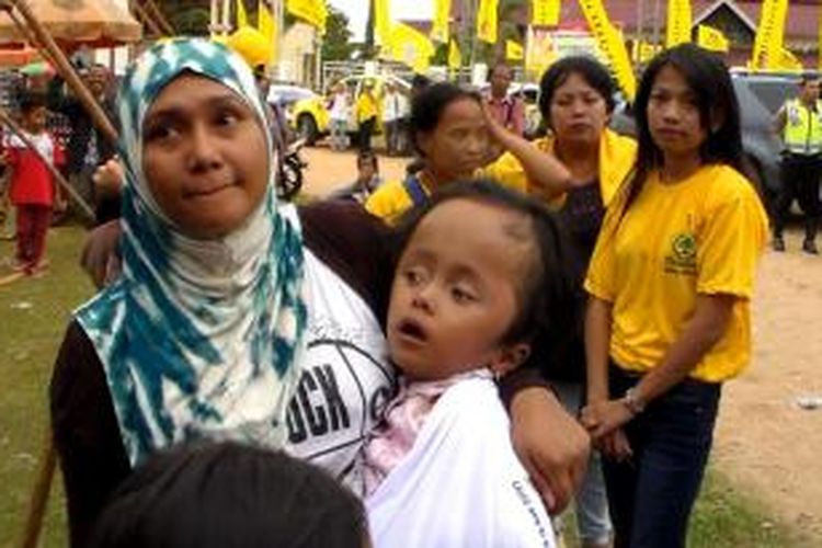 Rina membawa putrinya yang menderita Hidrosefalus ke lokasi kampanye partai Golkar di Palangkaraya, Kalimantan Tengah Selasa (25/03/2014).