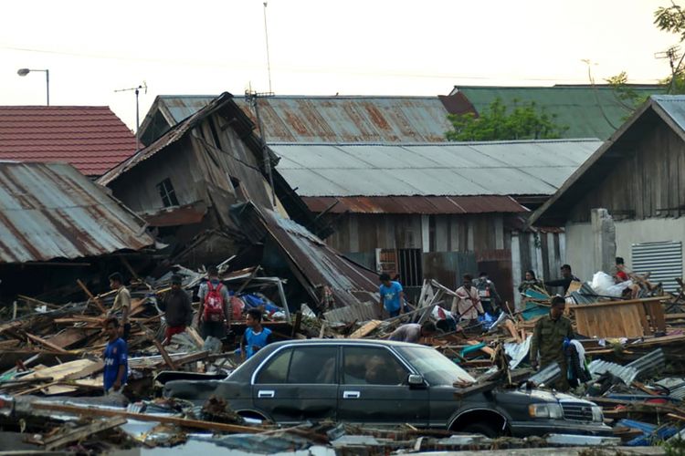 Warga berusaha menyelamatkan barang-barang dari rumah mereka yang runtuh akibat gempa bumi dan tsunami menghantam Palu, Sulawesi Tengah, Sabtu (29/9/2018). Hampir 400 orang tewas akibat gempa yang disusul tsunami pada Jumat (28/9/2018).
