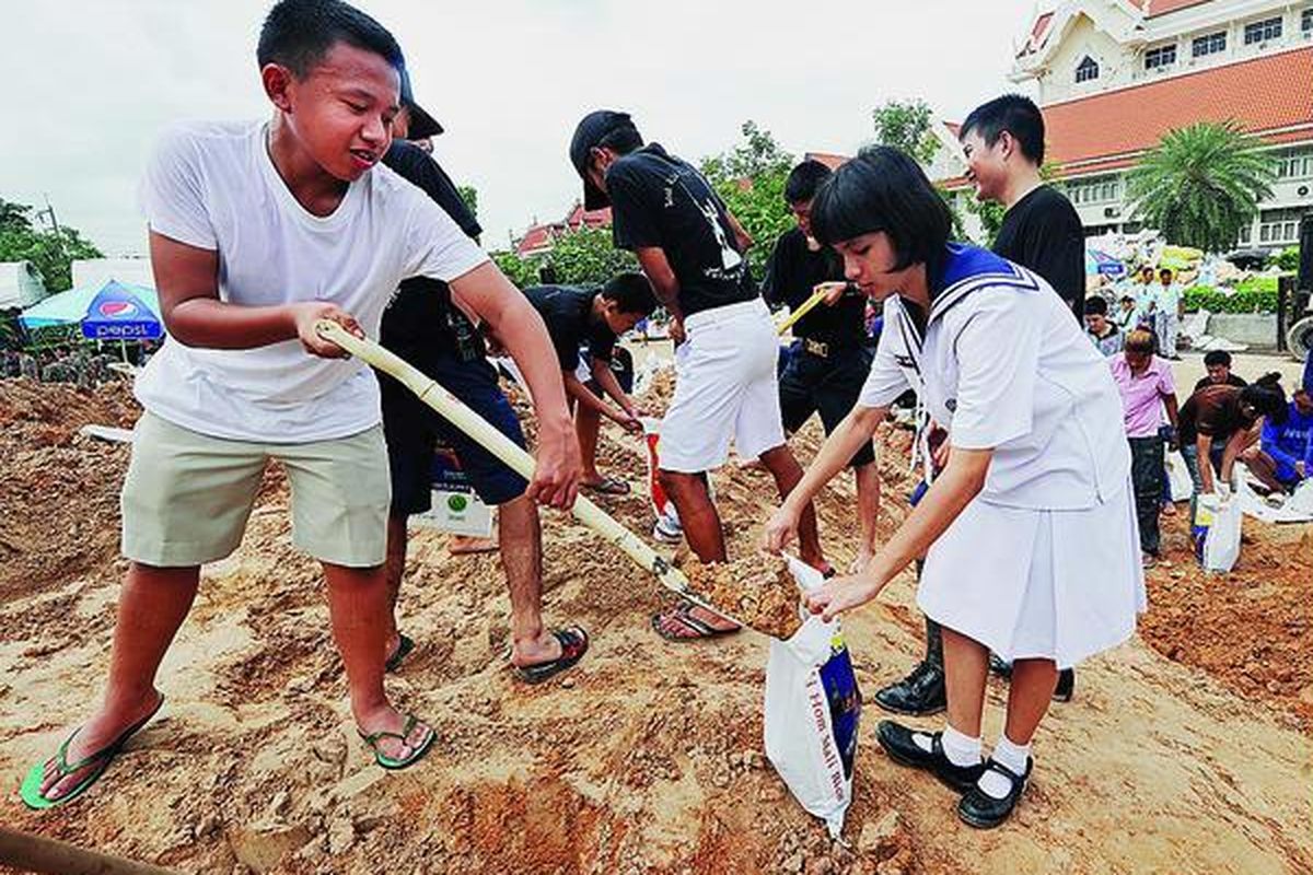 Siswa sekolah di Thailand bergabung dengan sukarelawan mengisi karung dengan pasir sebagai persiapan menghadapi banjir di Provinsi Pathum Thani, wilayah penyangga Bangkok, Kamis (13/10). Thailand kemarin mendeklarasikan provinsi ketiga sebagai daerah darurat bencana. Banjir terbesar yang melanda Thailand dalam satu dekade terakhir itu juga membuat manufaktur otomotif Toyota menghentikan produksi mereka.