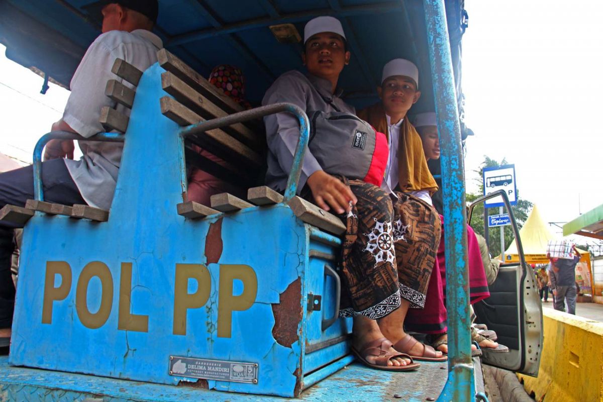 Sejumlah warga memanfaatkan mobil patroli Satpol PP DKI Jakarta di Jalan Jatibaru, Tanah Abang, Jakarta, Rabu (31/01/2018). Mobil tersebut tidak sengaja beroperasi karena karena operasional bus transjakarta Tanah Abang Explorer dihentikan sementara akibat aksi mogok yang dilakukan supir angkot Tanah Abang.