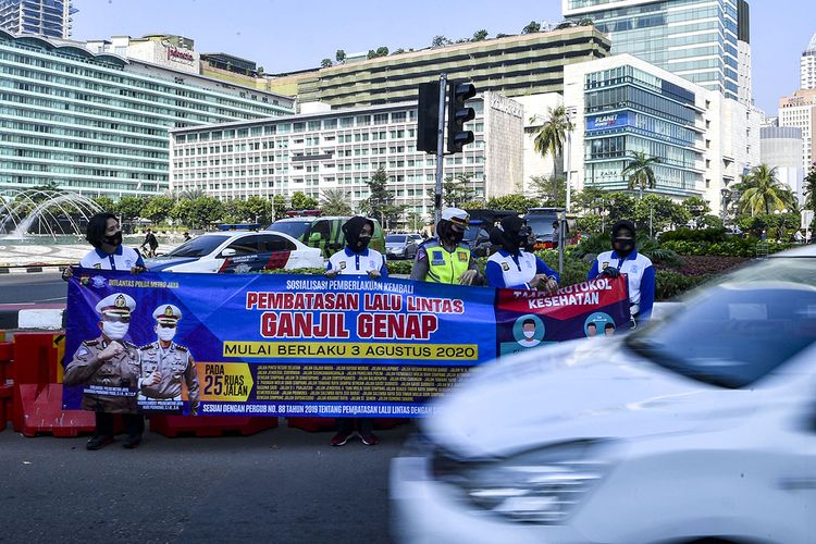 Sejumlah anggota Kepolisian membentangkan spanduk sosialisasi pemberlakuan kembali ganjil genap di Bundaran Hotel Indonesia, Jakarta, Minggu (2/8/2020). Pemprov DKI Jakarta menerapkan kembali aturan ganjil genap bagi kendaraan roda empat saat masa Pembatasan Sosial Berskala Besar (PSBB) transisi mulai Senin (3/8/2020) di 25 ruas jalan Ibu Kota.