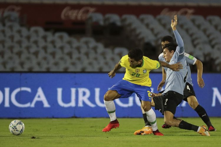 Duel perebutan bola antara Roberto Firmino (kiri) dan Jose Gimenez (kanan) dalam laga Kualifikasi Piala Dunia 2022 Zona Conmebol, Uruguay vs Brasil, di Estadio Centenario, Rabu (18/11/2020). 