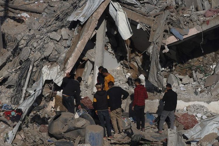 Warga Palestina memandangi puing-puing permukiman yang hancur di Rafah, selatan Jalur Gaza, setelah serangan udara Israel pada Senin (4/12/2023).