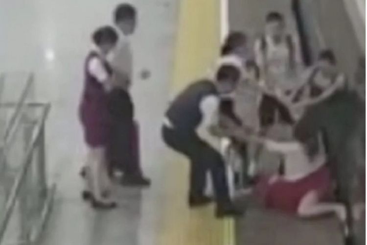Petugas stasiun di Guangzhou South, China, berusaha menarik seorang penumpang perempuan yang melakukan aksi berbahaya karena terlambat naik kereta pekan lalu.
